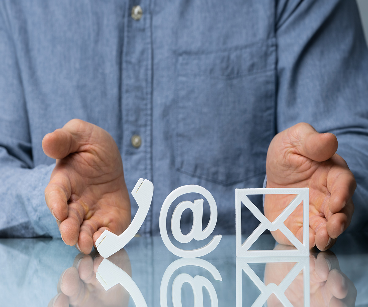 An individual s hands with a phone and an envelope symbolizing communication and mail, overlaid on a computer screen displaying a digital representation of the same items.